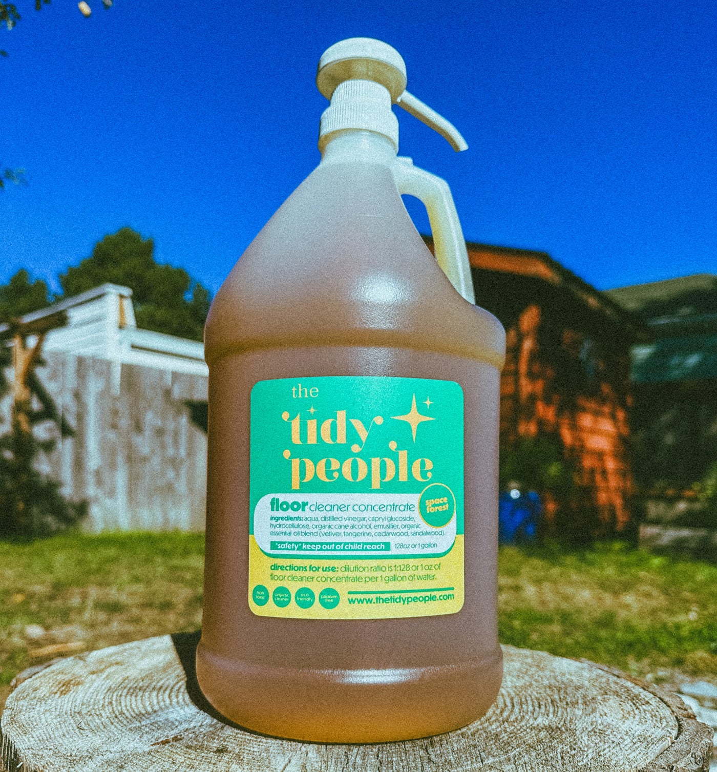 Bottle of 'the tidy people' cleaner on a wooden stump with a blue sky and building in the background